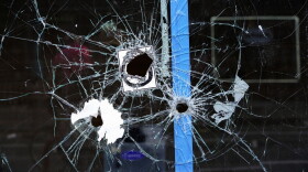 A storefront window with bullet holes is seen at the scene of a fatal shooting on South Street in Philadelphia on Sunday morning.