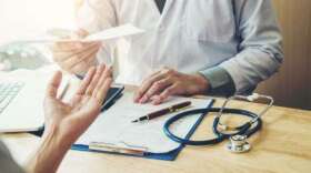 Doctor or physician writing diagnosis and giving a medical prescription to female Patient (IStockphoto/IStockphoto)