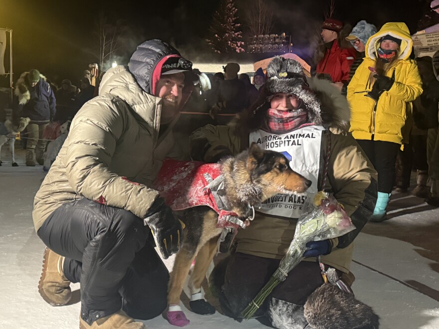 Yukon Quest Alaska 750 champion Josi Shelley poses with one of her lead dogs and husband J.J. after crossing the finish line Monday night at Pikes Landing in Fairbanks. (Patrick Gilchrist/KUAC)