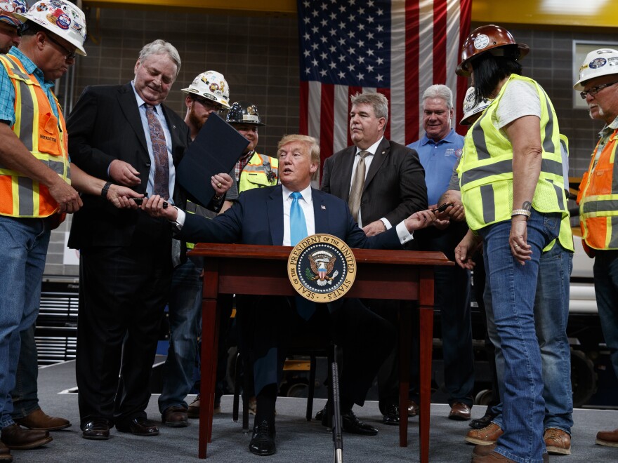 President Trump hands out pens after signing an executive order aimed at making it easier for companies to pursue oil and gas pipeline projects. The president addressed an audience at the International Union of Operating Engineers International Training and Education Center in Texas.