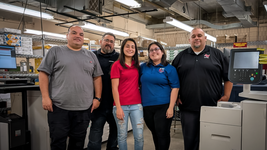 The Arizona Western College Print Services team poses for a group photo inside the campus print shop in Yuma, Arizona. From left to right: Scott Rico, Marco Castillo, Daniela Lopez Hernandez, Saghey Barcenas, and Saul Robles.