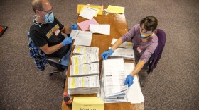 In this photo provided by Wisconsin Watch, election workers Jeff and Lori Lutzka, right, process absentee ballots at Milwaukee's central count facility on Aug. 11, 2020. (Will Cioci/Wisconsin Watch via AP)
