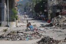 A youth crosses a street littered with garbage in downtown in Port-au-Prince, Haiti, Tuesday, Jan. 20, 2026. (AP Photo/Odelyn Joseph)