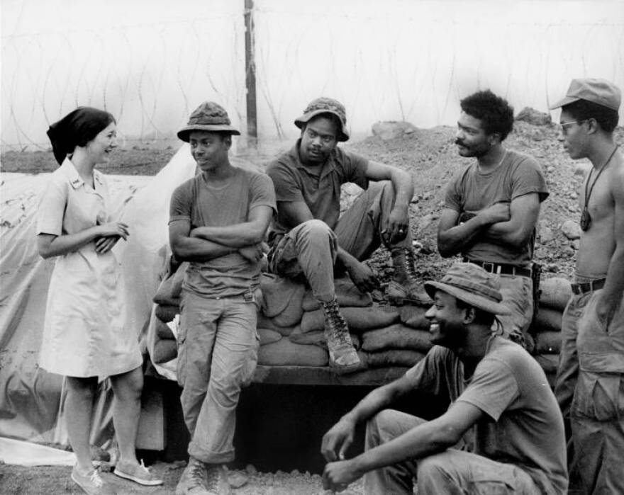 A Donut Dollie converses with a group of soldiers in Vietnam. Christine Campbell—the mother of Heather Collins—served for a year as a Donut Dollie during the Vietnam War.