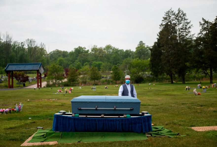 Imam Said Sherzadi  stands alone near the casket of Ghulam Merzazada, at the National Memorial park cemetery in Fairfax, Virginia.