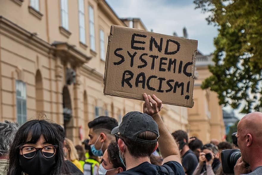 Protester holds up a sign that reads: End systemic racism.