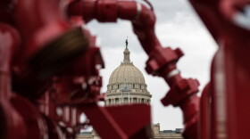 A demonstrator holds up seven fingers to send a message to a House committee that lawmakers should remove discounts and incentives so all oil and gas wells are taxed at 7 percent.