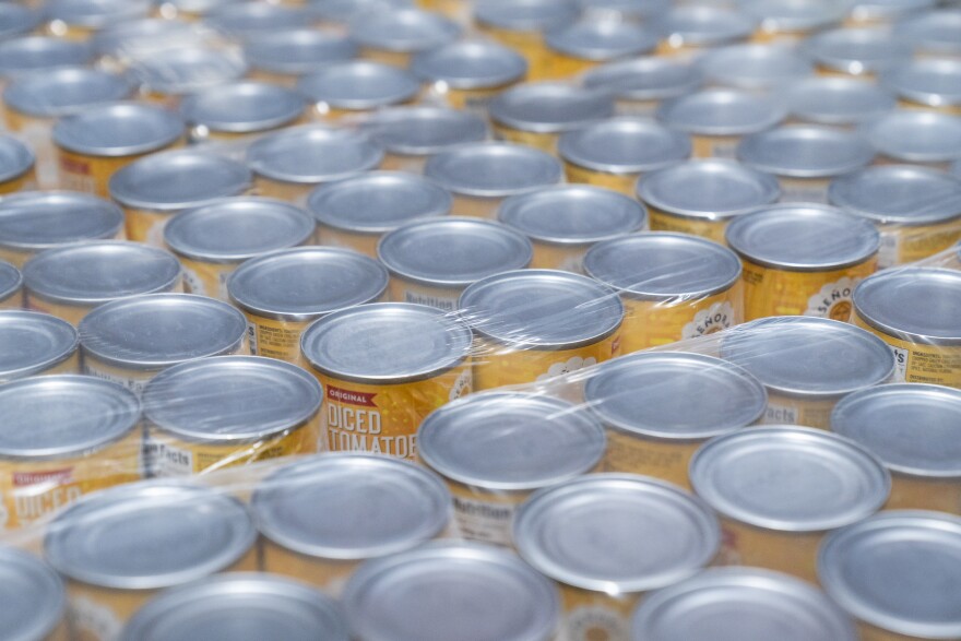 Cans of diced tomatoes lay wrapped in plastic as they're stored on pallets on racks in, March 2024, at Operation Food Search (OFS) in Overland. Food banks have seen an uptick in traffic since the lapse in SNAP benefits due to the ongoing federal shutdown.