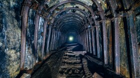 Dark abandoned coal mine with rusty miner stands.