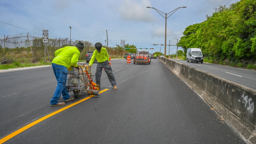 Employees from Lake’s Trucking and Heavy Equipment perform road striping last month on Melvin H. Evans Highway.