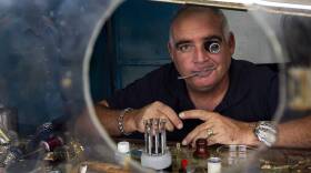 LOOKING FOR THE U.S.: A private Cuban watch repair shop owner peers out of his business in Havana.