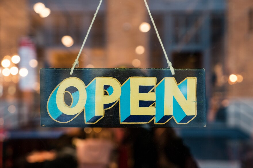 Open vintage wooden sign broad through the glass of store window. Filtered image.