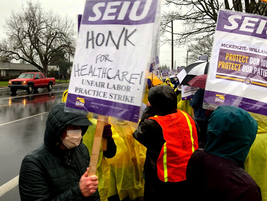 Picketers march and chant through the rain outside McKenzie-Willamette Medical Center.