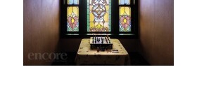 A chess set sits in front of a stained glass window at the Marlborough building