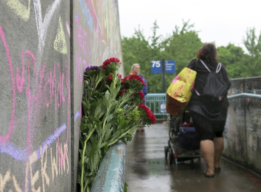 Commuters walk past a rain-soaked memorial on Tuesday to two men who were fatally stabbed after trying to stop another man who went on an anti-Muslim tirade against two young women in Portland, Ore.