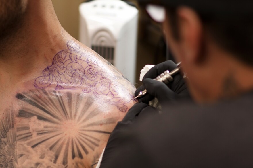 Freddy Negrete, 61, works on a tattoo on a customer's shoulder.