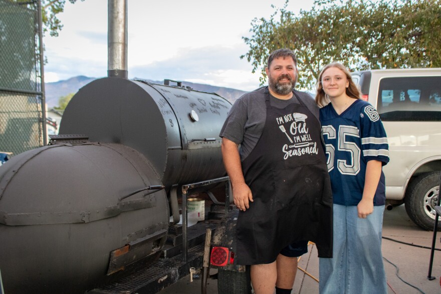 Jaren Larsen stands with his daughter, Eliza, next to the smoker he built, Sept. 26, 2025.