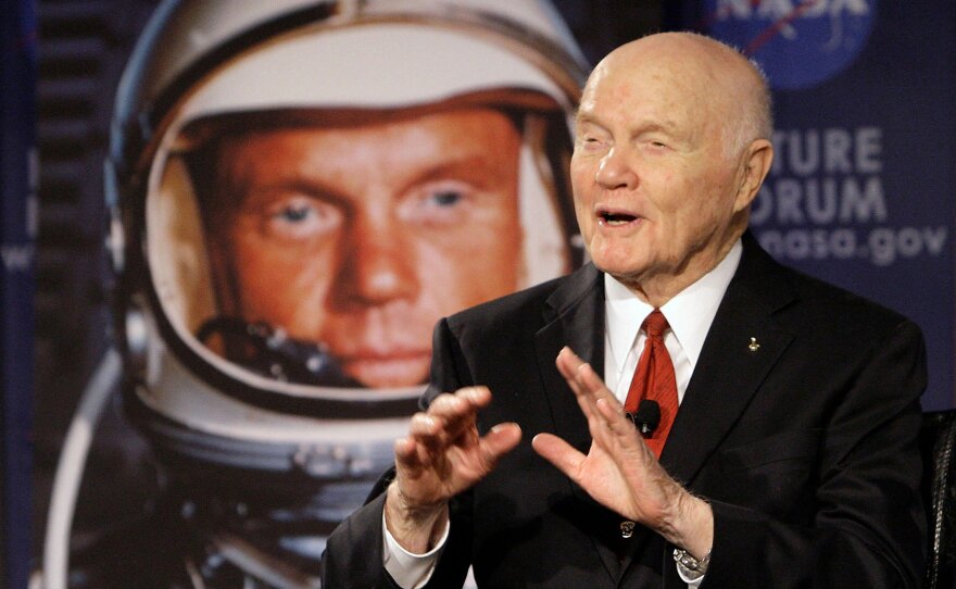 John Glenn speaks in front of an image of him as an astronaut in 1962.