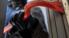 Thief holding a crowbar to break a glass window