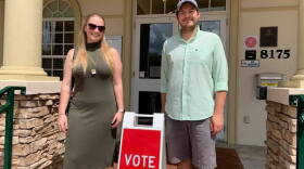 Woman and man stand next to Vote sign