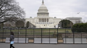 A woman walks past security fencing protecting the West Front of the U.S. Capitol in Washington, Friday, Jan. 8, 2021, as preparations take place for President-elect Joe Biden's inauguration after supporters of President Donald Trump stormed the building.
