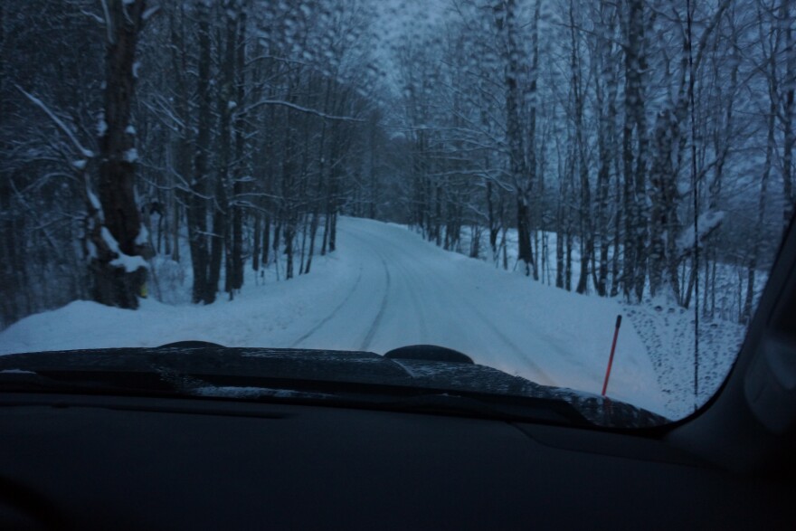 View out front of a truck with snow and trees ahead 