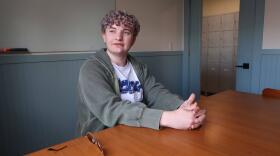 Boy sits at table with fingers intertwined together