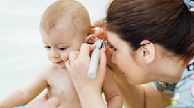 Woman pediatrician is examining little baby's ear