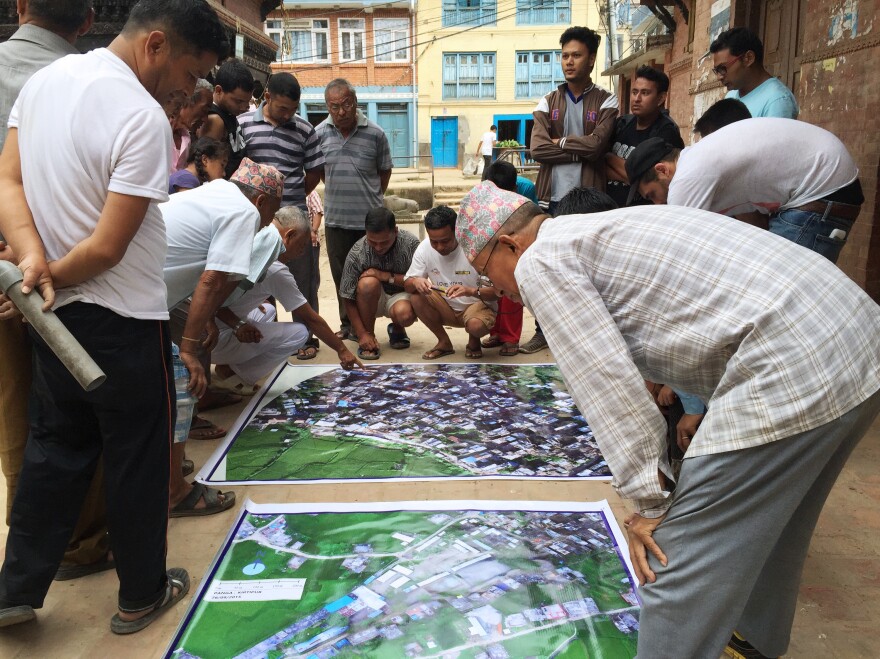 Residents of Panga, a town in Nepal hit hard by the 2015 earthquake, study a map of their area put together with drone images that Meier and his partners gathered.