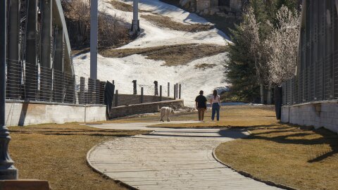 People walk across a grassy section of Park City’s Town Lift Plaza that’s often covered with snow at this time of year, March 19, 2026.