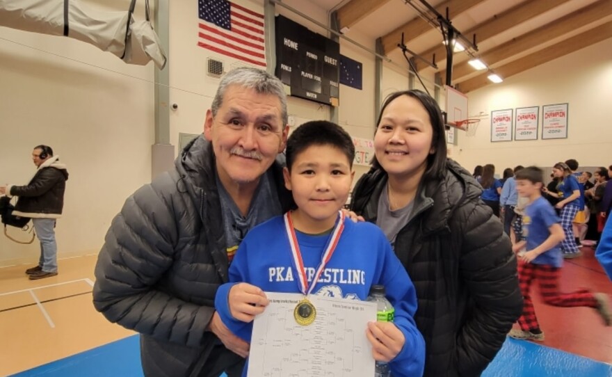 Joe Bavilla, Juanita Martin and Napaskiak wrestler Bradley Chaney, celebrating his first place tournament finish.