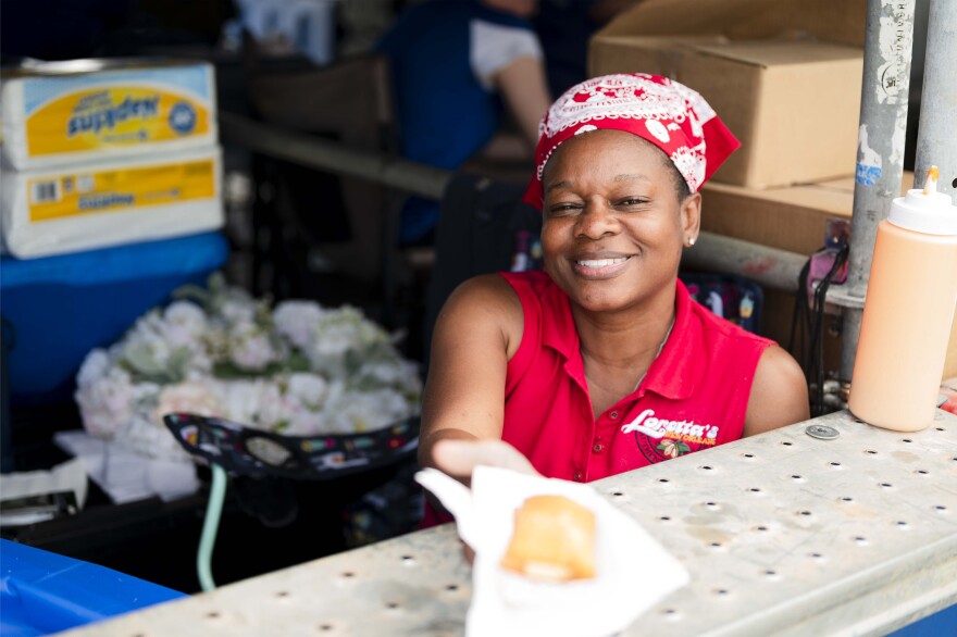 A food vendor from Loretta’s Authentic Pralines serves praline-stuffed beignets at the New Orleans Jazz and Heritage Festival on April 29, 2022.