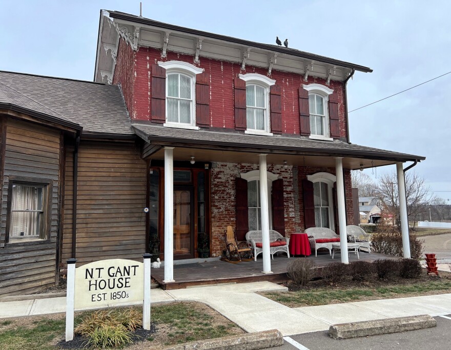A two-story home has red shutters and a big, open front porch.
