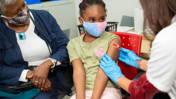 A CVS pharmacist applies a band-aid after giving a vaccine to a child.