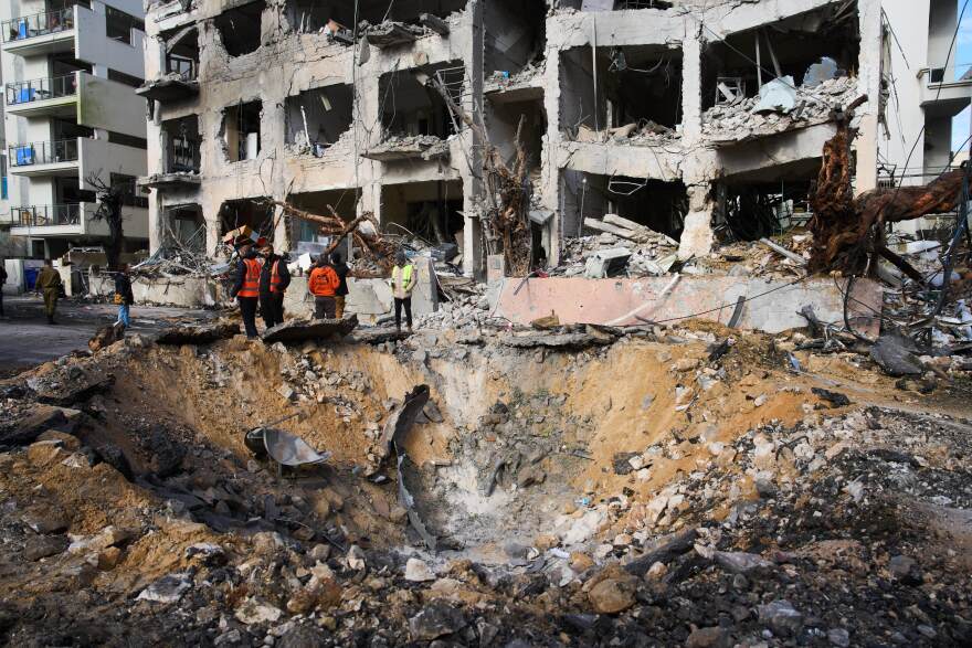 Rescue workers and military personnel survey the scene of a direct hit a day after an Iranian missile struck in Tel Aviv, Israel, Sunday, March 1, 2026. (AP Photo/Oded Balilty)