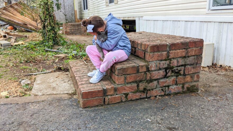 Rios’ granddaughter, Aubree, hugs Scratchy, a cat that lived at the WC Mobile Home Community.