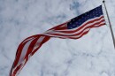 United States Flag waving in the wind amidst a cloudy sky