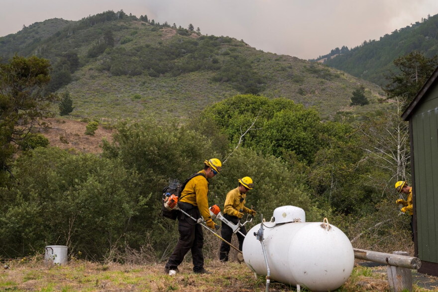 Crews trim bushes around the U.S. Forest Service fire station to help protect structures from the Plaskett Fire near Big Sur, Calif., Thursday, Aug. 27, 2026.