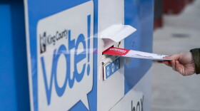 A person puts their ballot in a drop box.
