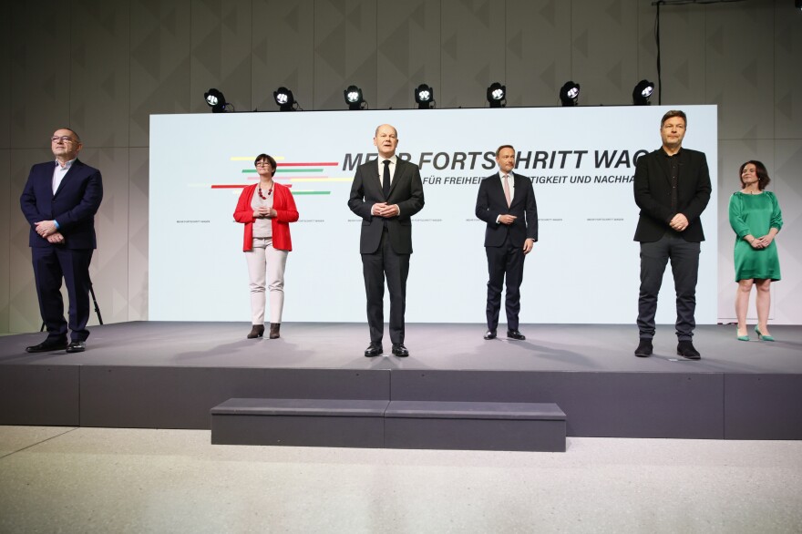 Olaf Scholz (center) and Saskia Esken (second left) of the Social Democrats, Annalena Baerbock (right) and Robert Habeck (second right) of the Greens and Christian Lindner (third right) of the Free Democrats pose for photos after signing a coalition agreement between the three parties on Tuesday in Berlin. [Carsten Koall / Getty Images]