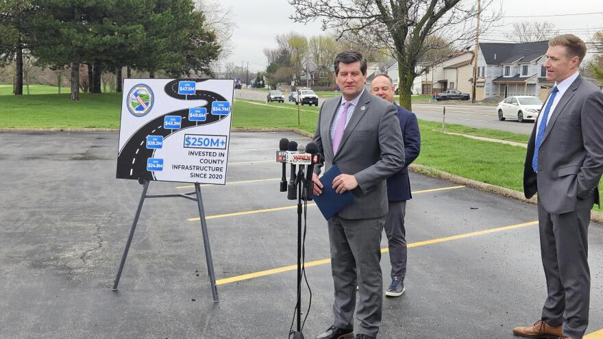 Erie County Executive Mark Poloncarz stands in front of the microphone during a press conference, detailing county plans for 2026 road improvements.