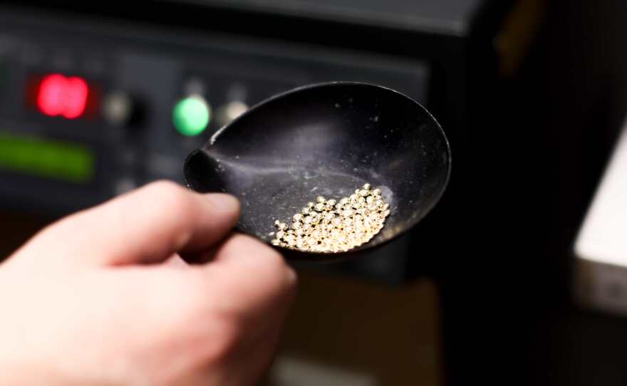 a hand holds a round bowl filled with metal material