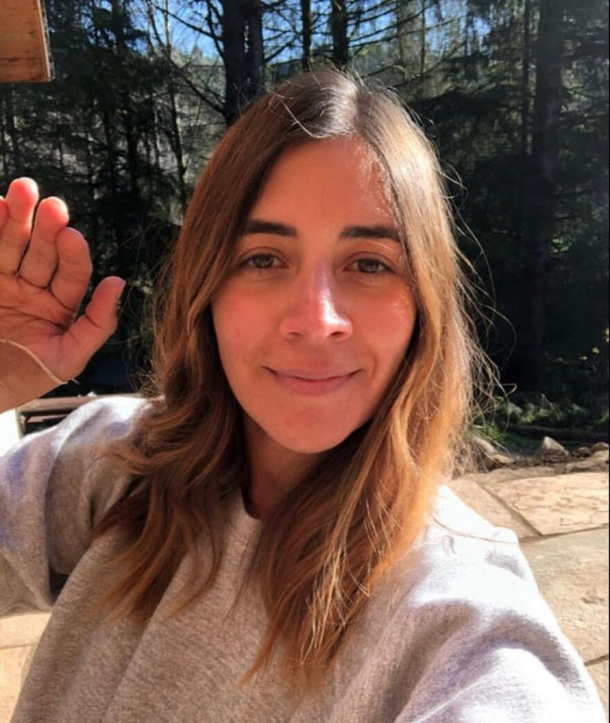 Woman waving and looking into camera.