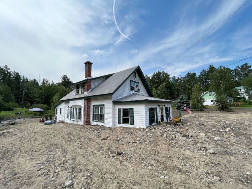 A white house sits surrounded in mud and rocks.