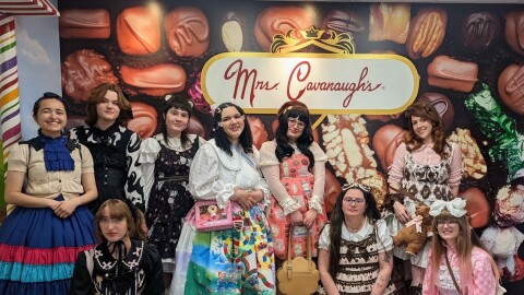 A group of people in colorful dresses, with large, poofy skirts and sleeves. 