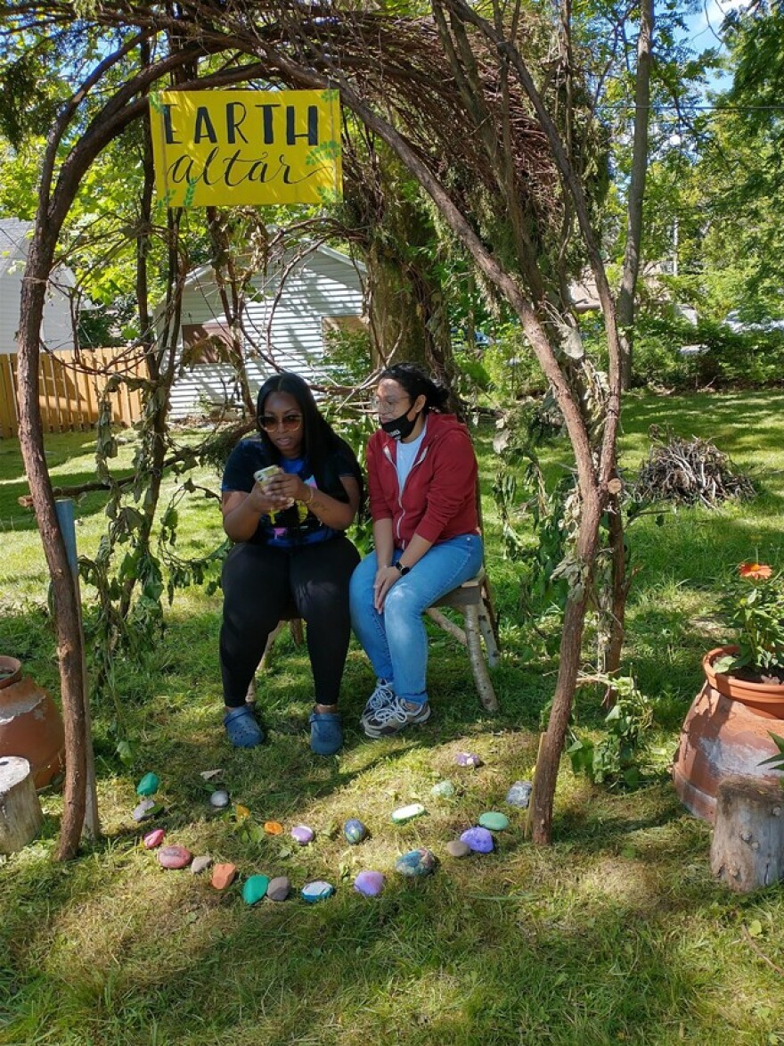 Youth educators Natasha Morrison and Alex Hubble sit at the Earth Altar they created outside of the Gandhi Institute in Rochester.