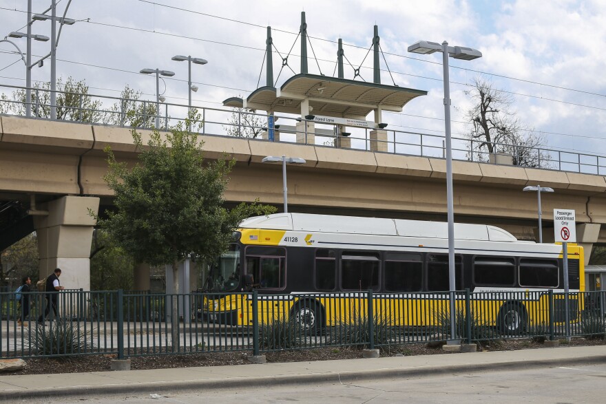 A bus pulled up to the station with a few people walking toward it.