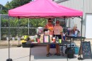 Two women stand in a pop-up tent where they are serving dirty sodas