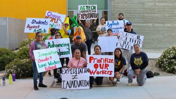 Farmworkers and UC Merced students pose with signs outside a side door Dr. Vikram and Priya Lakireddy Grand Ballroom at UC Merced on Friday, March 23, 2026.