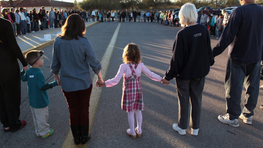Five-year-old Rachel Crabb (center) holds hands with  teachers, parents and other students during a moment of silence for her slain  schoolmate, Christina Green, at Mesa Verde Elementary School in Tucson, Ariz., earlier this week.